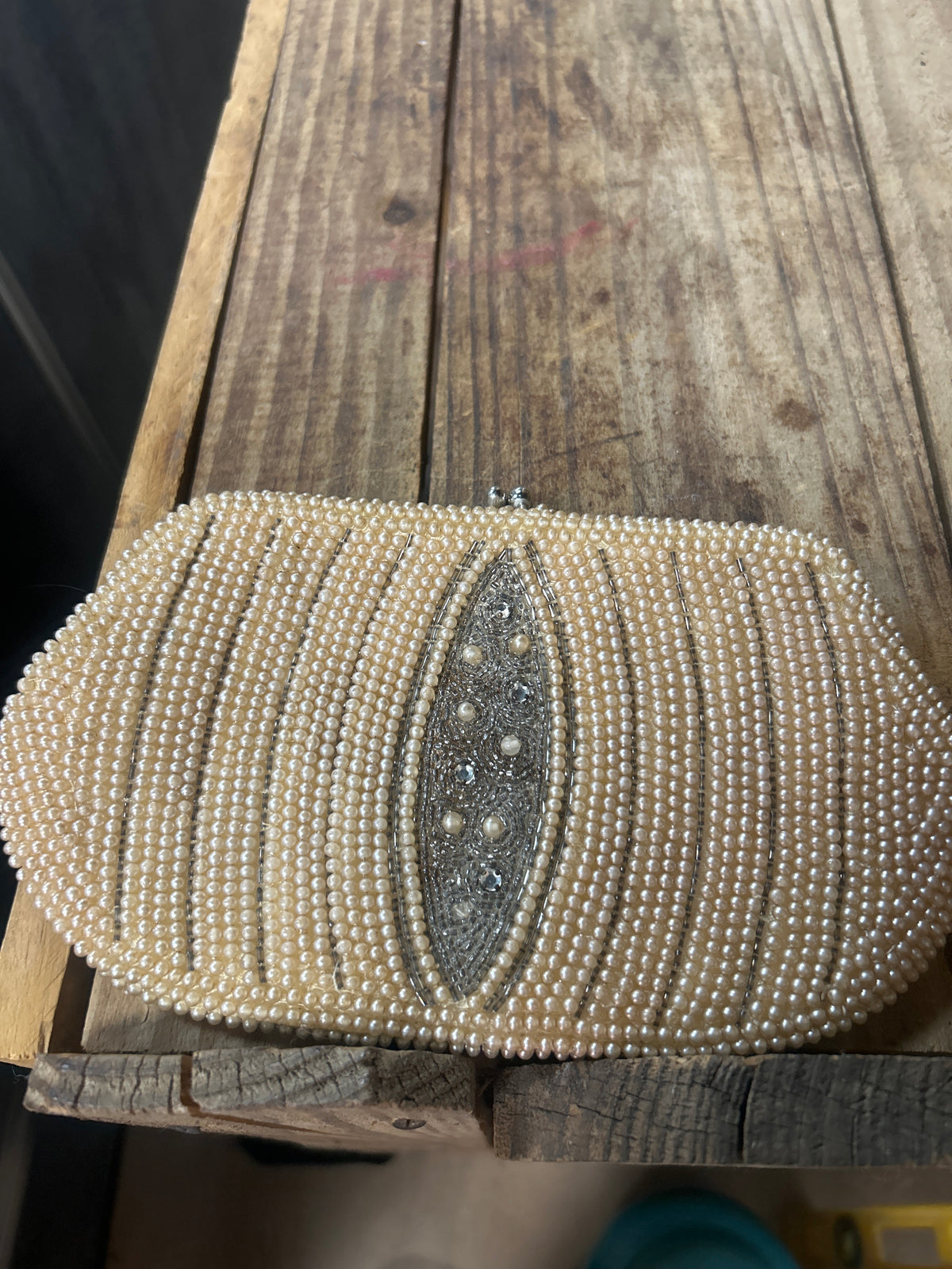 Ivory pearl beaded clutch features a unique silver-toned center embellishment and resembles vintage 1950s evening bags.