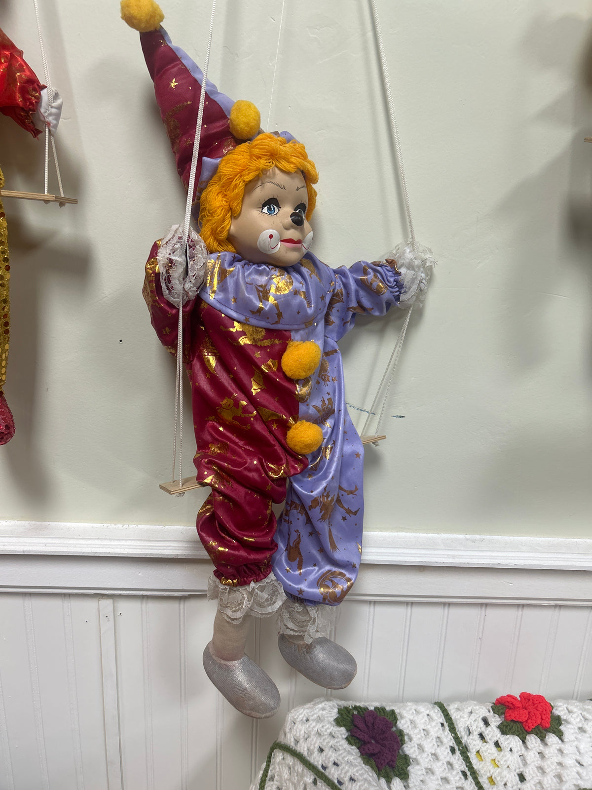 Vintage porcelain head clown doll features a soft body dressed in a red and lavender satin costume adorned with a metallic gold star pattern