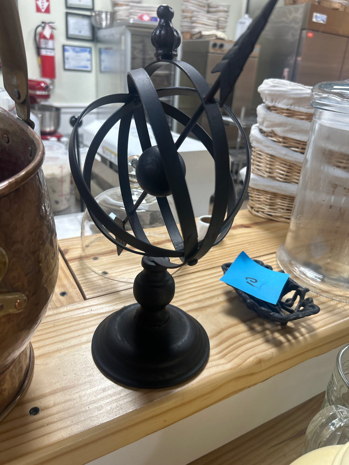 Matte black metal armillary sphere concentric rings and an arrow pointing upward
