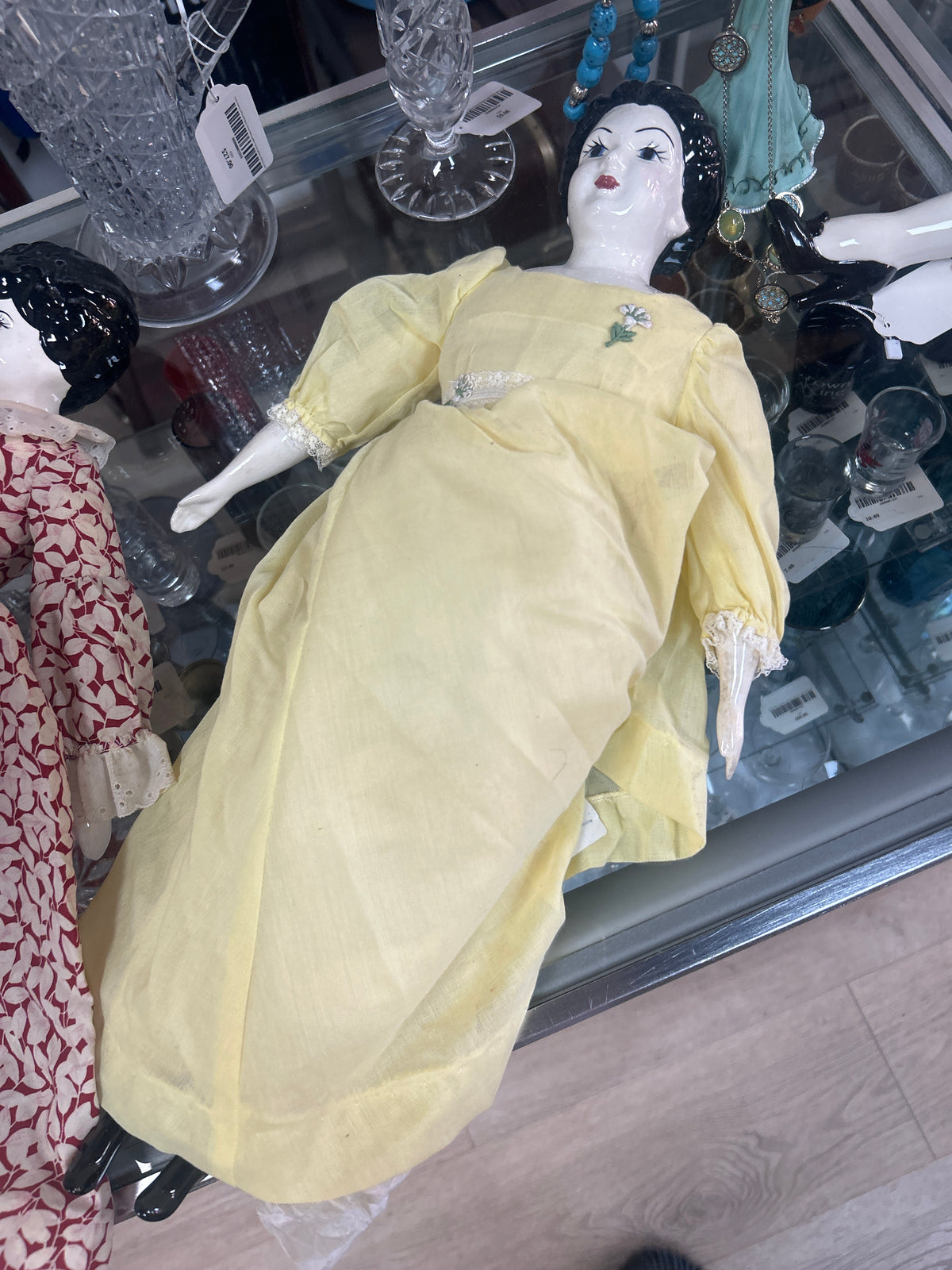 antique-style doll features a glazed china head with painted features and molded black hair, resembling popular 19th-century German designs, Yellow dress