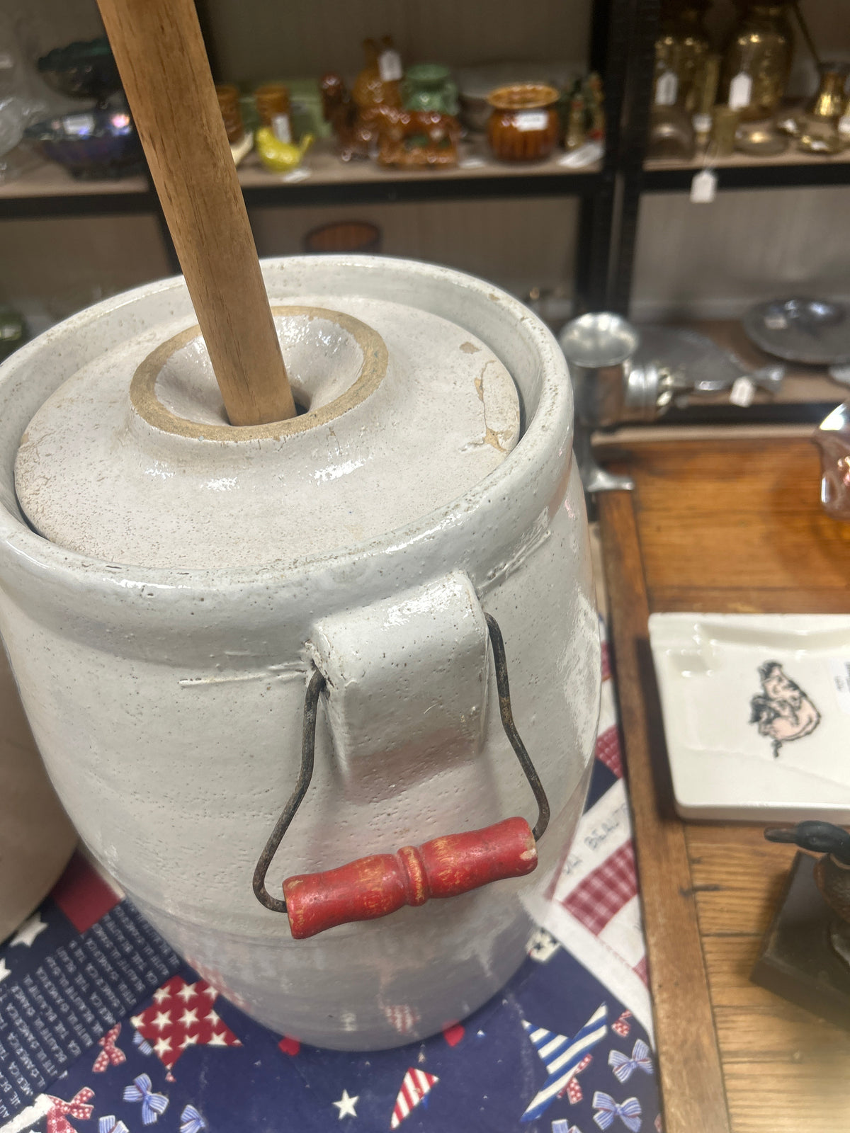 an antique white stoneware butter churn with a wooden dasher and wire bail handle