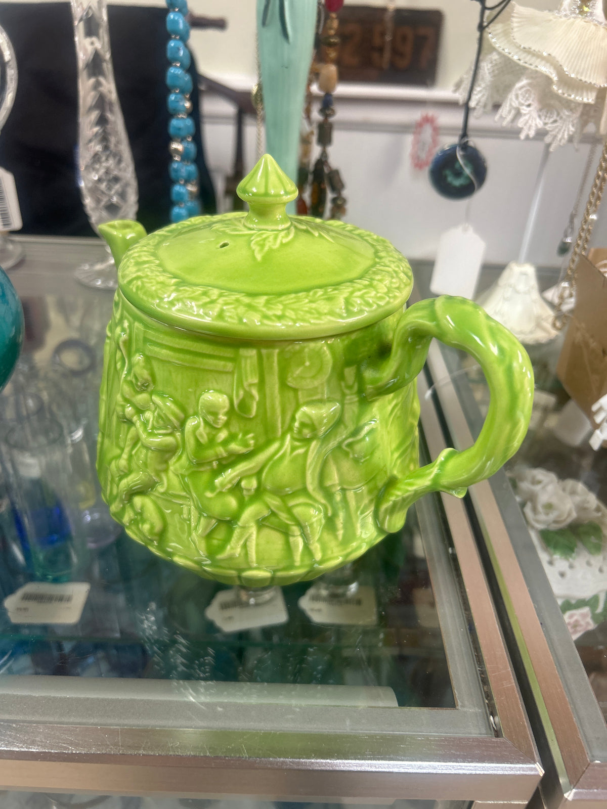 Vintage ceramic teapot features a vibrant green majolica glaze with an embossed "Tavern and Witches" scene