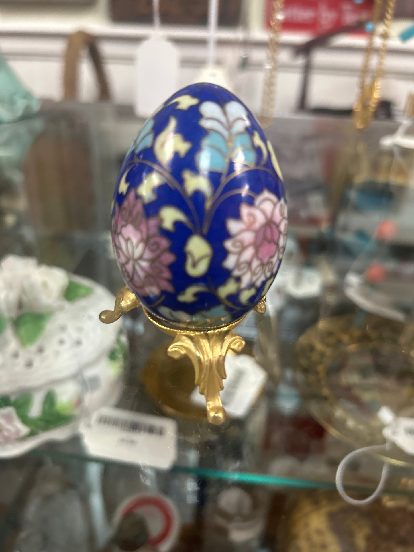 vintage cloisonné egg features intricate floral designs on a blue enamel background, paired with a delicate gold-toned metal stand