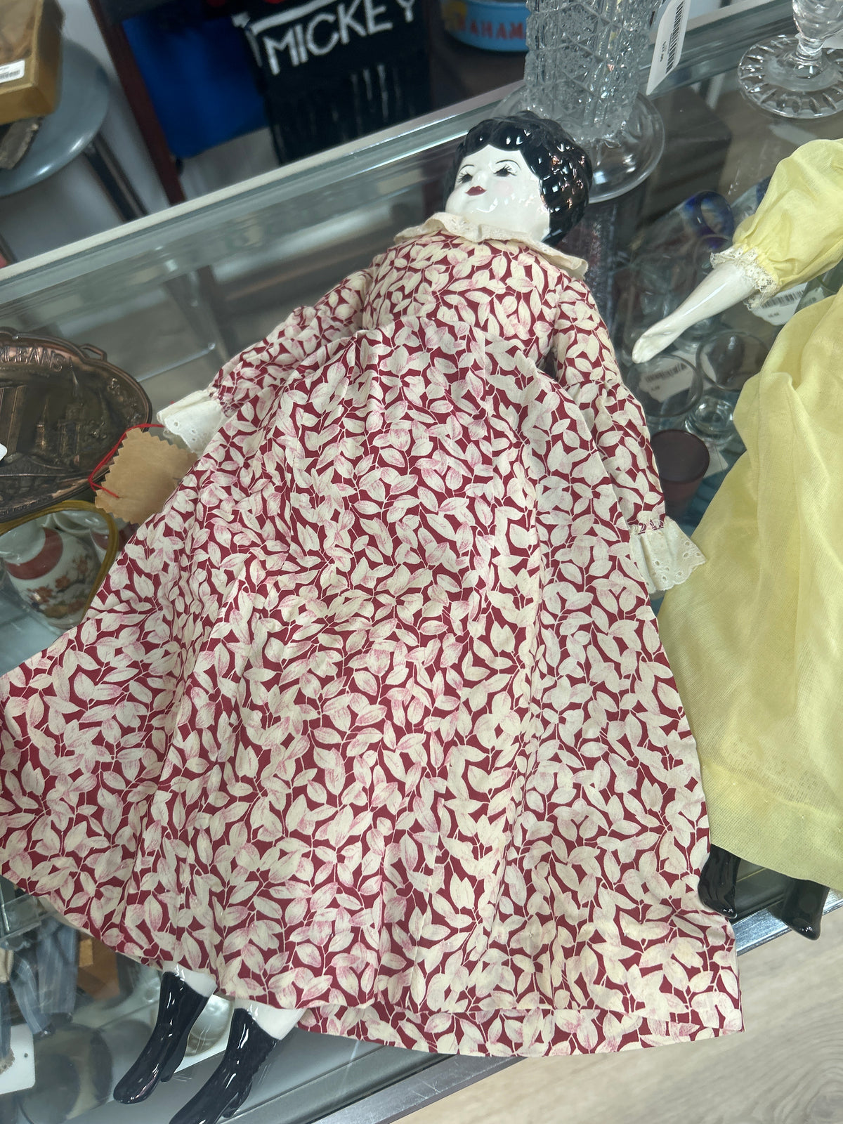 antique-style doll features a glazed china head with painted features and molded black hair, resembling popular 19th-century German designs, Floral dress