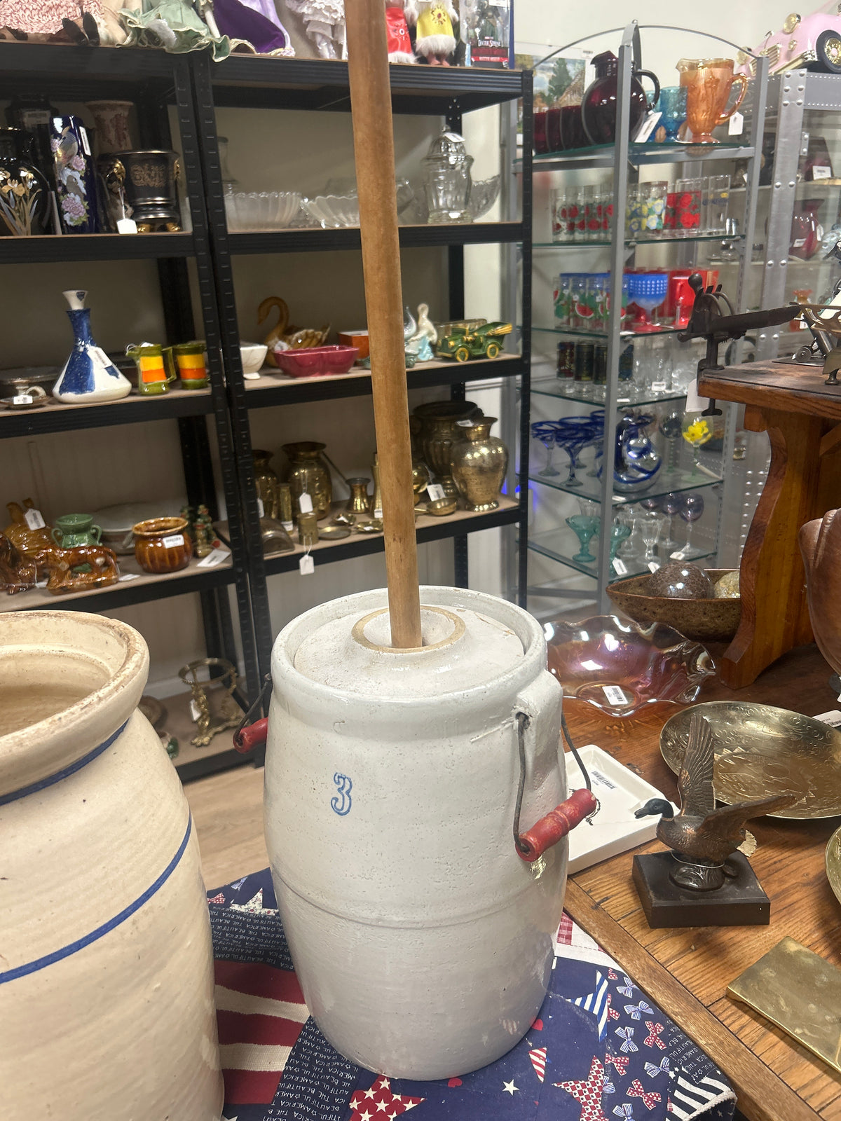 an antique white stoneware butter churn with a wooden dasher and wire bail handle