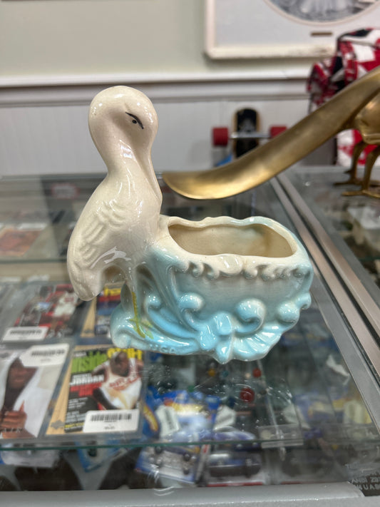 Vintage stork ceramic planter with blue accents grazing.