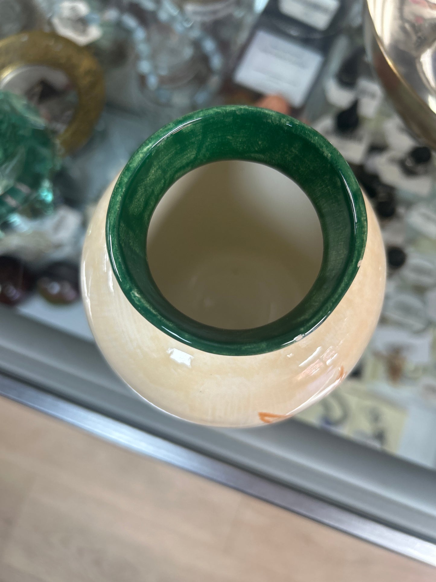 creamy-white ceramic vase features painted orange sun and blue spirit figure designs with a dark green rim